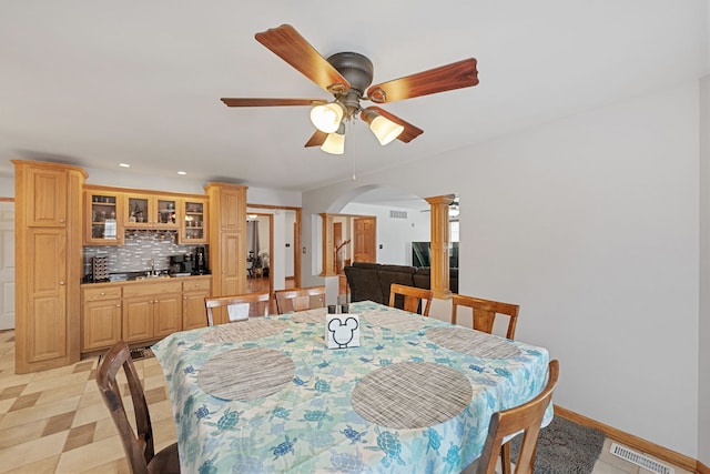 dining room with ceiling fan, sink, and ornate columns