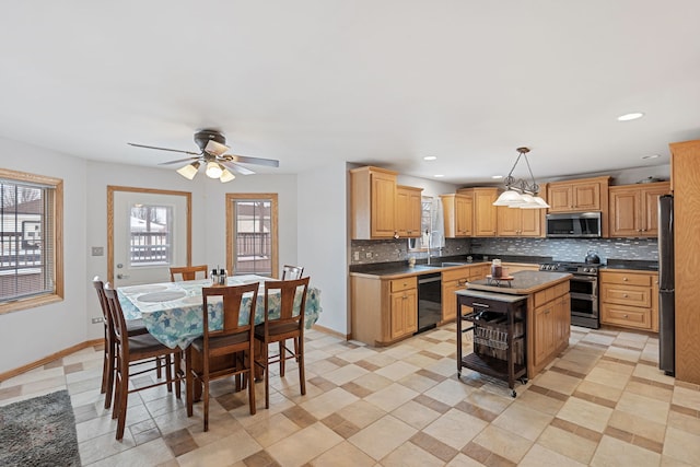 kitchen with a center island, appliances with stainless steel finishes, hanging light fixtures, sink, and ceiling fan