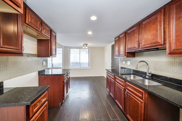 kitchen with dark stone countertops, dark hardwood / wood-style floors, tasteful backsplash, and sink