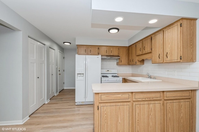 kitchen with light hardwood / wood-style floors, kitchen peninsula, decorative backsplash, sink, and white appliances