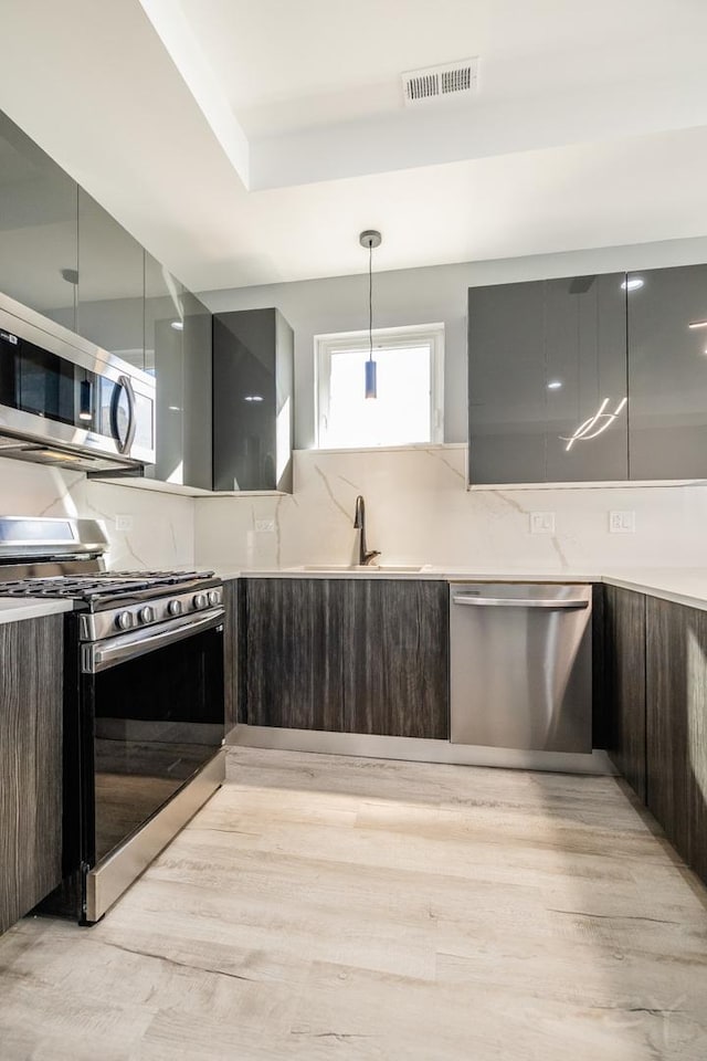 kitchen with sink, hanging light fixtures, dark brown cabinets, and appliances with stainless steel finishes