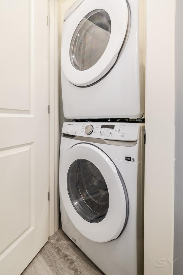 laundry area featuring stacked washer and dryer and light wood-type flooring