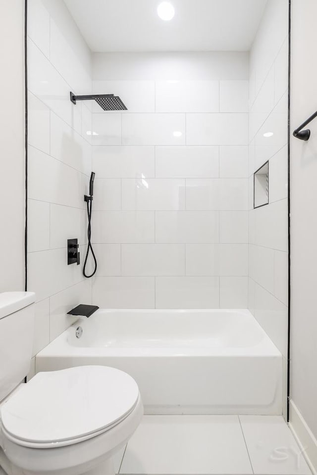 bathroom featuring toilet, tiled shower / bath combo, and tile patterned floors