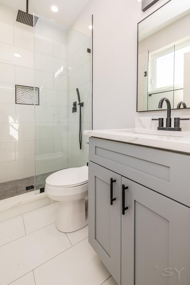 bathroom featuring toilet, vanity, tile patterned floors, and a shower with shower door