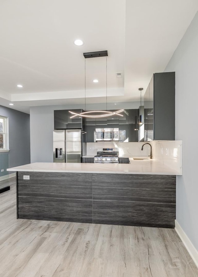 kitchen featuring kitchen peninsula, appliances with stainless steel finishes, pendant lighting, and sink