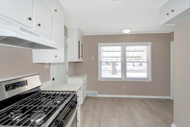 kitchen featuring light wood-type flooring, stainless steel range with gas cooktop, white cabinetry, and ornamental molding