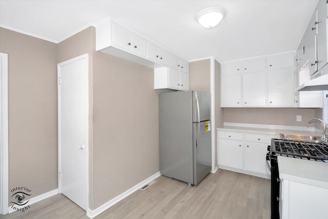 kitchen featuring sink, stainless steel refrigerator, white cabinetry, light hardwood / wood-style flooring, and range with gas stovetop