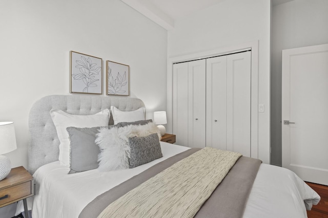 bedroom with beam ceiling, a closet, and hardwood / wood-style flooring