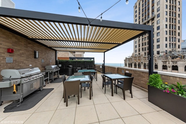 view of patio featuring grilling area, a pergola, and a water view