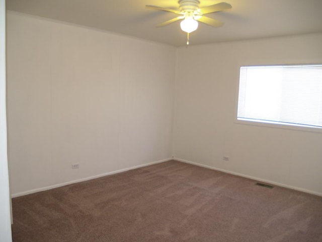 spare room featuring ceiling fan and dark colored carpet