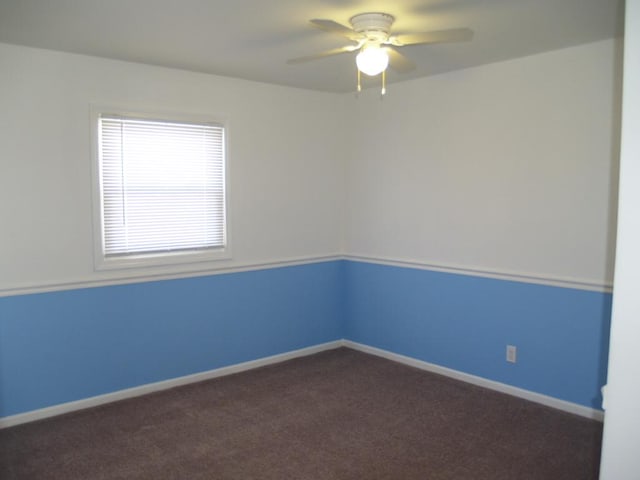 spare room with dark colored carpet and ceiling fan