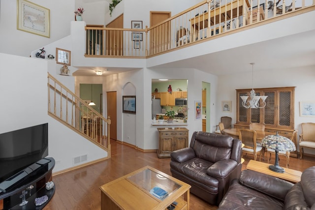 living room featuring hardwood / wood-style flooring, a high ceiling, and a chandelier