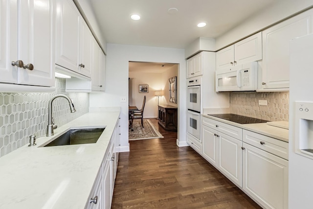 kitchen with white cabinetry, white appliances, dark wood-type flooring, light stone countertops, and sink