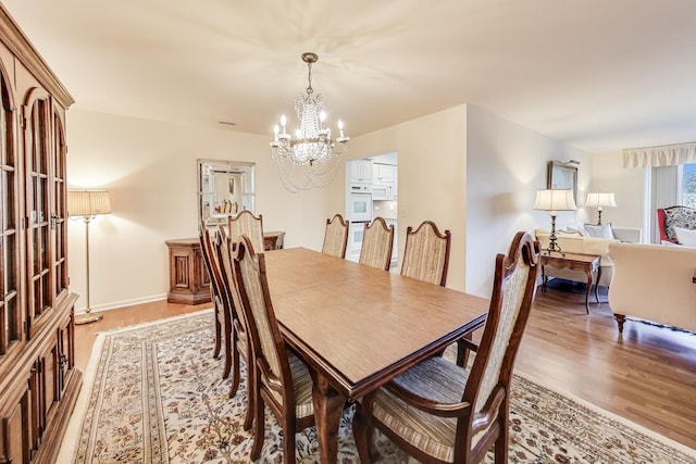 dining space with hardwood / wood-style floors and a chandelier