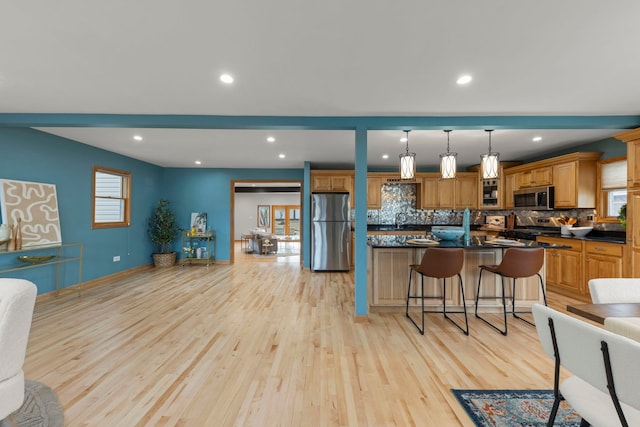 kitchen featuring dark countertops, a breakfast bar, stainless steel appliances, and light wood-style flooring