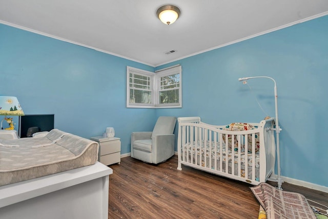 bedroom with a nursery area, dark wood-type flooring, and crown molding