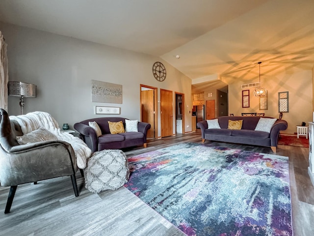 living room with an inviting chandelier, vaulted ceiling, and dark wood-type flooring