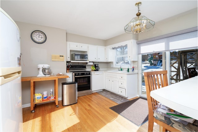 kitchen with white dishwasher, pendant lighting, white cabinets, gas range, and sink