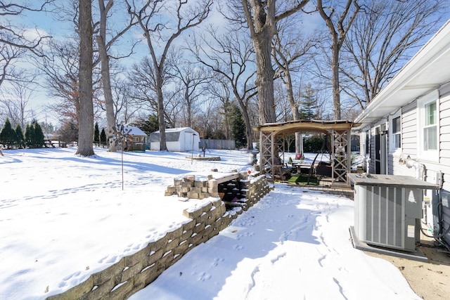 snowy yard featuring central AC and a storage shed