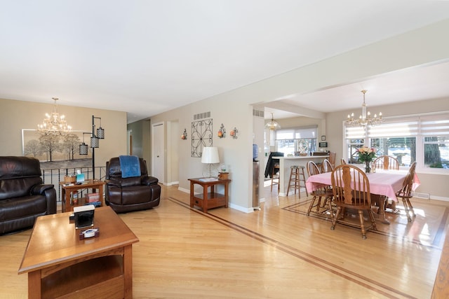 living room with a chandelier, light wood-type flooring, and a healthy amount of sunlight