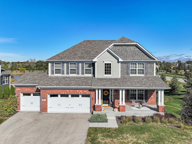 view of front of property featuring a front yard, a garage, and covered porch