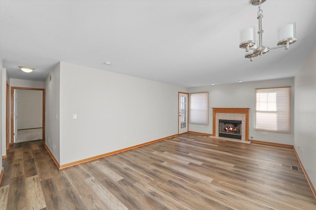 unfurnished living room featuring wood-type flooring and a chandelier