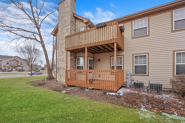 rear view of house featuring a balcony, central air condition unit, and a lawn