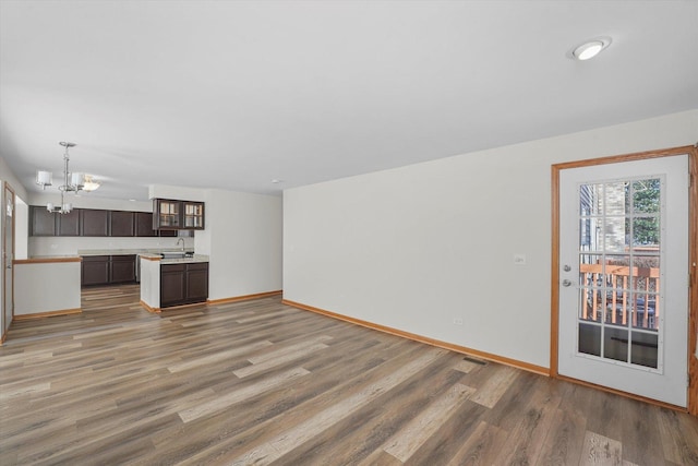 unfurnished living room featuring dark hardwood / wood-style floors, sink, and a notable chandelier