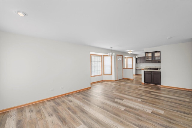 unfurnished living room with a notable chandelier and light hardwood / wood-style flooring