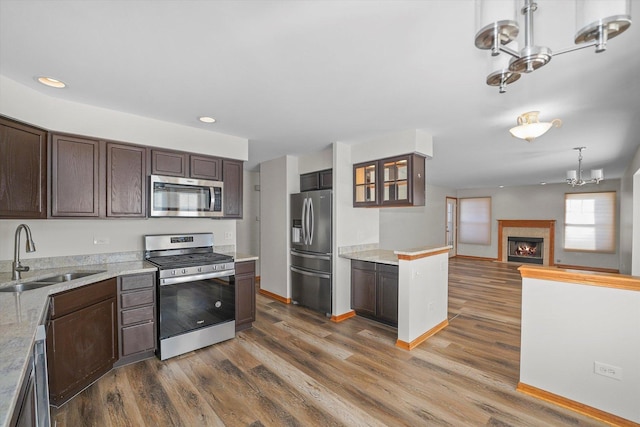 kitchen with appliances with stainless steel finishes, decorative light fixtures, dark wood-type flooring, dark brown cabinetry, and sink