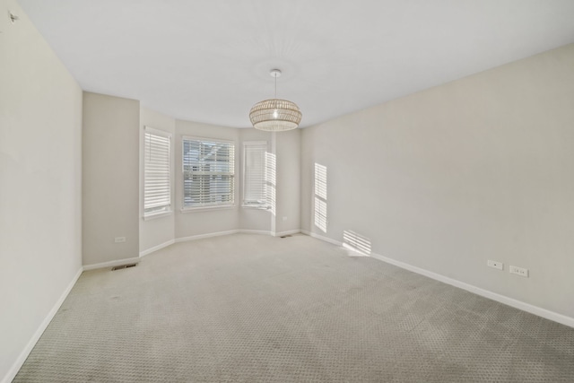 empty room featuring a notable chandelier and light colored carpet