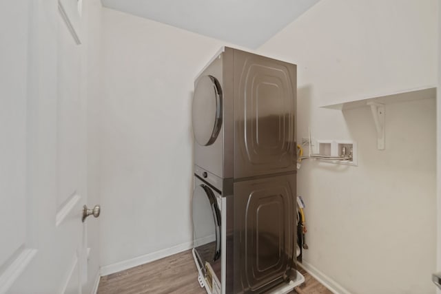 clothes washing area with stacked washer / dryer and light hardwood / wood-style flooring