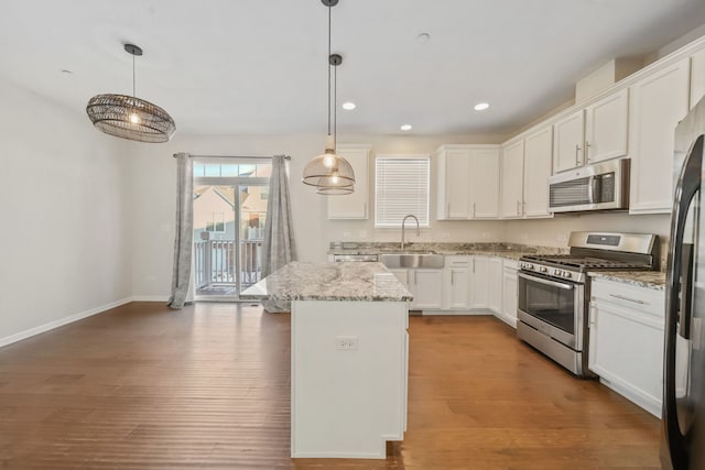 kitchen featuring sink, white cabinets, a center island, pendant lighting, and appliances with stainless steel finishes