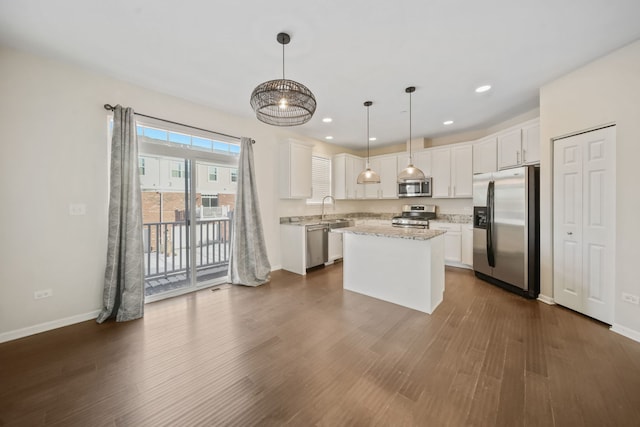 kitchen featuring stainless steel appliances, white cabinets, a center island, and hanging light fixtures