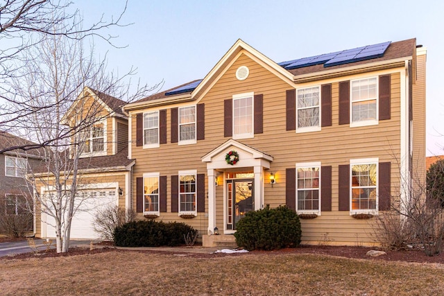 colonial inspired home with a garage and solar panels