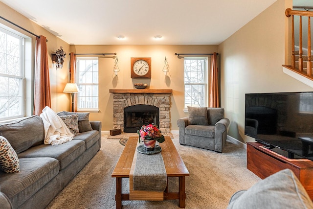 living room with a stone fireplace, carpet flooring, and a wealth of natural light