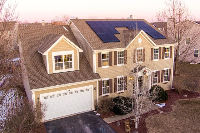 view of front facade with a garage and solar panels