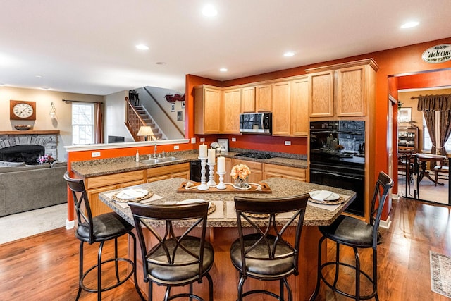 kitchen with sink, wood-type flooring, black appliances, and kitchen peninsula