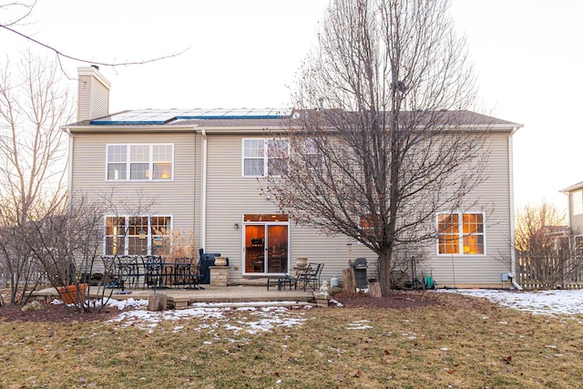 snow covered rear of property with a patio area and a lawn