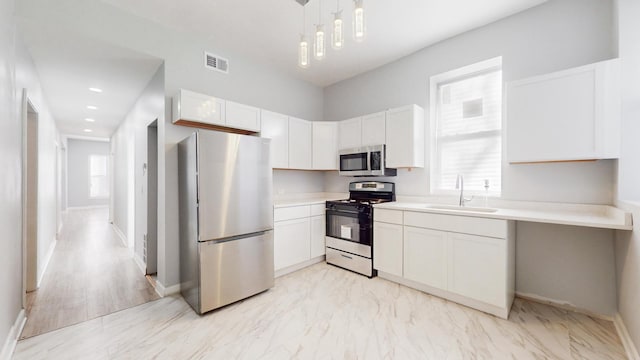 kitchen with appliances with stainless steel finishes, sink, white cabinetry, and pendant lighting