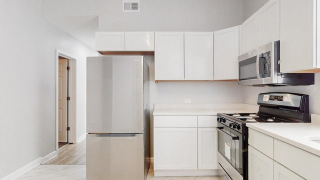 kitchen featuring fridge, gas stove, and white cabinetry