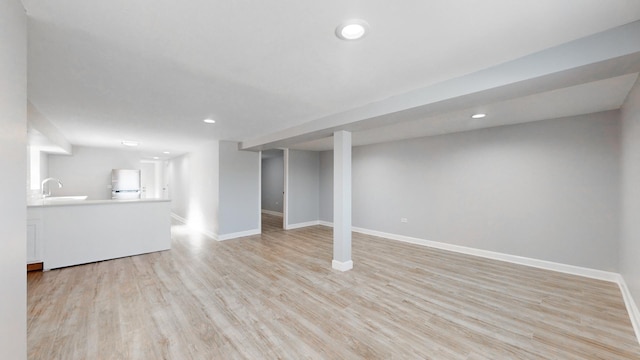 basement featuring fridge, sink, and light wood-type flooring