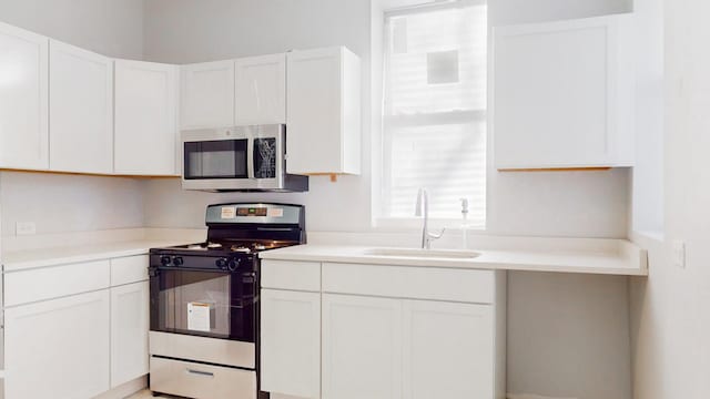 kitchen featuring stainless steel appliances, white cabinetry, and sink