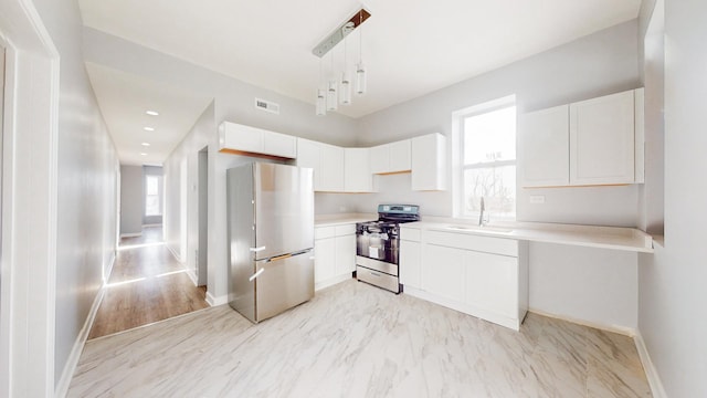 kitchen with appliances with stainless steel finishes, white cabinetry, decorative light fixtures, and sink