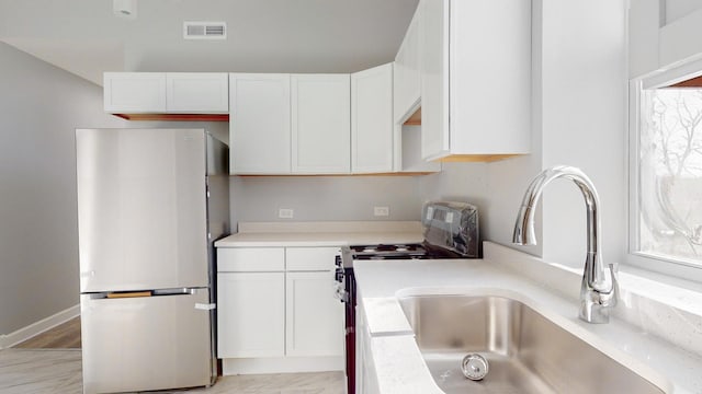 kitchen featuring appliances with stainless steel finishes, white cabinetry, and sink