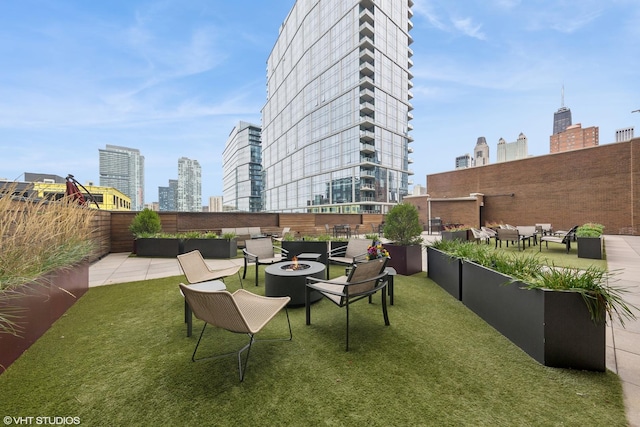 view of yard featuring a view of city, a patio area, and an outdoor living space with a fire pit