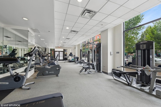 workout area featuring a wall of windows, a drop ceiling, visible vents, and recessed lighting