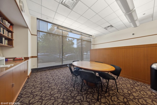 dining area with wood walls, a wall of windows, and visible vents