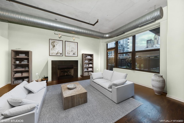 living area featuring dark wood-style floors, a view of city, baseboards, and a tile fireplace