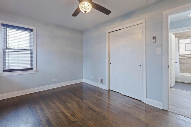 unfurnished bedroom with ceiling fan, dark hardwood / wood-style flooring, and multiple windows